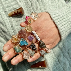 Detail of handmade gold wire wrapped natural crystal rings featuring colorful raw stones