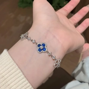 Luxe blue zircon flower bracelet in white gold finish worn on a female wrist