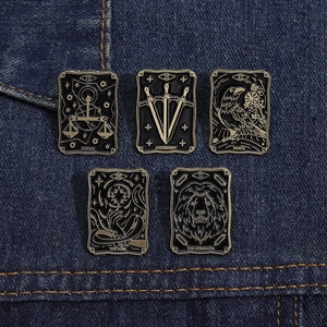 Detail of five vintage black enamel tarot badges on dark blue denim fabric texture