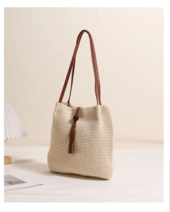 Detail of knit crochet tote bag with brown leather straps and wooden bead tassels