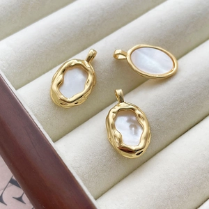 Close-up of three 14k gold-filled oval shell pendants with hammered texture on a tray