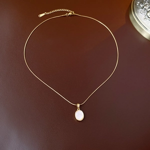 Détail macro d'un collier doré avec nacre blanche sur un fond en cuir luxueux