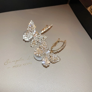 Detailed close-up of golden butterfly earrings featuring intricate zircon micro-pave setting