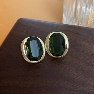 Macro view of vintage oval gold-plated earrings with emerald green zircon gemstones