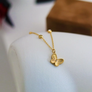 Golden butterfly necklace with radiant texture and zircon on a minimalist display