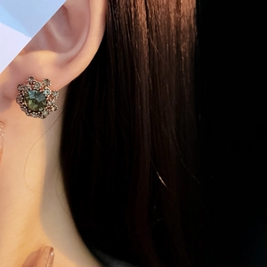 Detail of vintage flower stud earrings with green center stone and champagne crystals