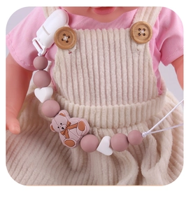 Close-up of pink bear silicone pacifier clip with heart beads on baby clothing