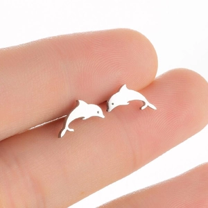 Close-up of small polished silver dolphin stud earrings held on a fingertip