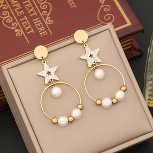 Golden star hoop earrings with white pearls and sparkling rhinestones on jewelry box