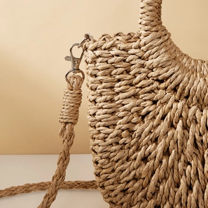 Macro detail of hand-woven straw bag texture with metallic lobster clasp and woven strap