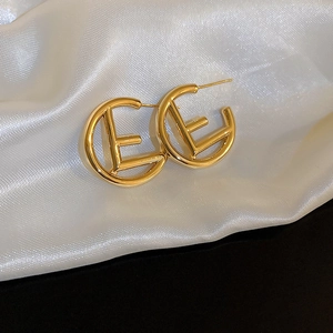 Elegant gold metal letter E geometric earrings on white silk fabric for stylish women