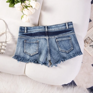 Detailaufnahme blauer Denim-Shorts mit Fransenrand und Gesäßtaschen auf weißem Sofa