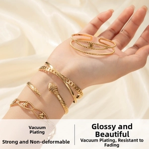 Detailed close-up of stacked gold snake bracelet and chains on a silk fabric background