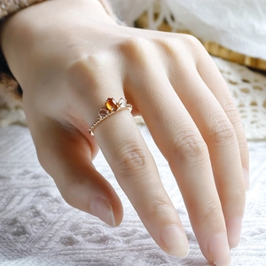 Detalle de anillo en plata 925 bañada en oro con granate naranja y cristales en encaje