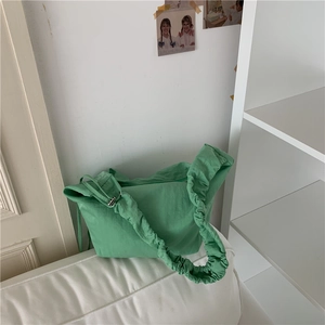 Dettaglio della borsa a mezzaluna in nylon verde lime con tracolla arricciata