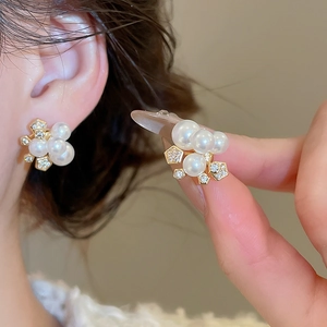 Détail de boucles d'oreilles fleuries plaquées or avec perles et zircons