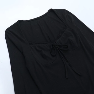 Detailed view of the square neckline with delicate lace trim and ribbon bow on black top