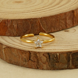 Gold stainless steel open ring with a sparkling star-shaped zircon on wooden background