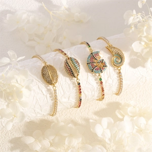 Detailed macro of gold adjustable bracelets featuring seashell charms with colorful zircon