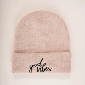 Close-up of the light pink beanie with black good vibes embroidery on the knit fabric