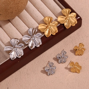 Detail of 18K gold and silver flower stud earrings in large and small sizes on a tray