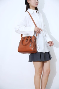 Brown woven shoulder bag with leather texture and fringe tassel detail on model
