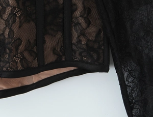 Detailed macro view of black lace overlay on nude lining with satin bound hem finishing