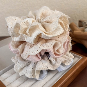 Lace ruffle scrunchies in beige, pink, and blue colors on a wooden jewelry tray