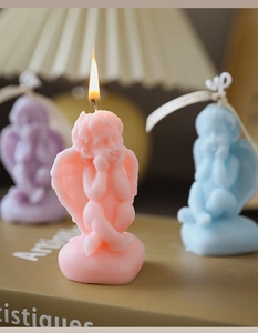 Detailed view of three colored cherub angel soy wax candles in pink, blue, and purple