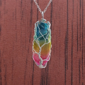 Silver tree of life wire-wrapped necklace with colorful crystal pendant on wooden background