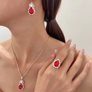 Elegant gold-tone jewelry set with red teardrop stones and white crystals on a model