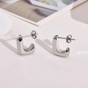 Vue macro de boucles d'oreilles minimalistes en acier titane argenté de forme géométrique