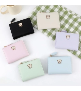 Flat lay of small bear wallets in six pastel colors featuring embossed cartoon patterns