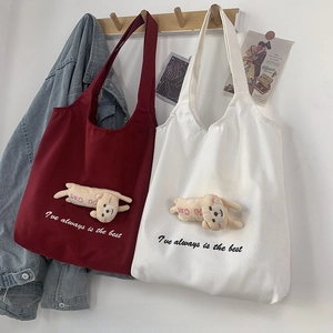 Detail of canvas tote bags with cute 3D plush puppy dolls and minimalist printed letters