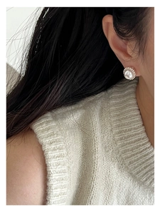 Detailed view of pearl earrings with metallic bead frame worn by a female model