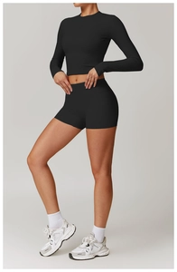 Détail d'un ensemble de yoga noir avec haut court à manches longues et short taille haute