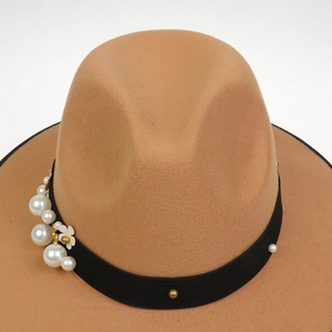 Close-up of brown wool fedora hat featuring black ribbon with pearl and floral charms