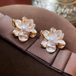 Elegant flower pearl earrings with white enamel petals and gold edges on silk ribbon
