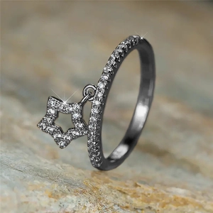 Macro shot of black gold star charm ring with shimmering pavé zircon details