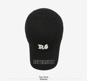 Detailed top view of black cotton baseball cap with white Ré and REVERSION embroidery