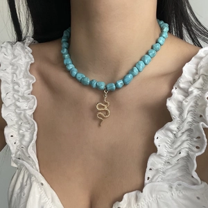Bohemian turquoise bead necklace with a gold snake pendant on a model wearing white lace