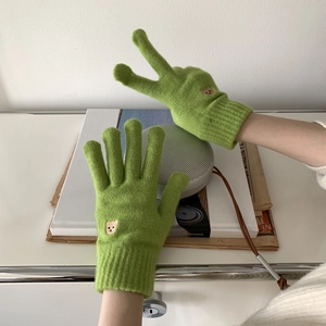 Close-up of green knitted gloves featuring cute brown bear embroidery and touch screen design