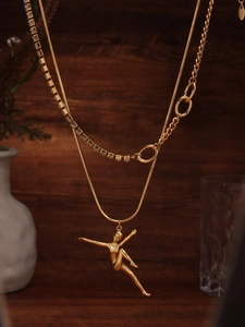 Detail of gold layered necklace featuring a dancing girl pendant and sparkling zircons