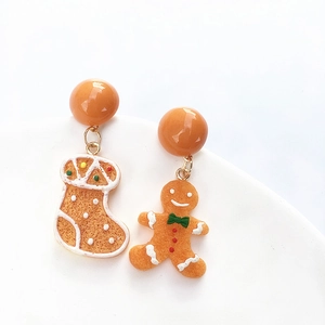 Detailed close-up of asymmetric Christmas gingerbread man and festive stocking earrings