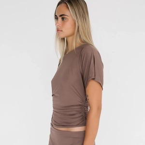 Détail du t-shirt marron avec coutures froncées et tissu élastique ajusté