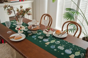 Detailed view of dark green Christmas table runner with festive bells and snowflake patterns