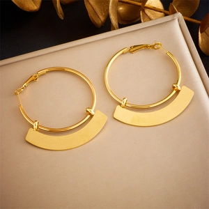 Detailed view of geometric gold earrings with curved metal pendants on leather surface