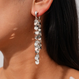 Détail de boucles d'oreilles pendantes argentées avec disques métalliques polis