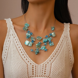 Close-up of multilayered beaded shell necklace with blue crystal accents on a model