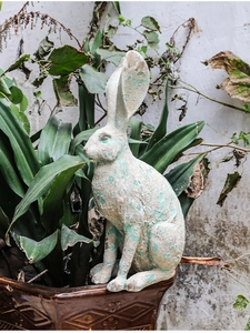 Detail of vintage resin rabbit statue with distressed white texture on a ceramic pot